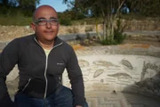 Dr. Mounir Fantar next to a sea themed mosaic in the garden of the House of Nymphs