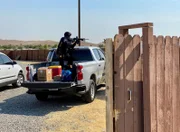 Police officer in back of truck during raid.