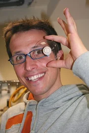 Willi mit einem Rohbrillenglas. Heute darf er einem Optiker über die Schulter schauen, der die Gläser dann in Form bringt.