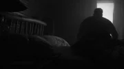 Der Mann sitzt im Dunkeln auf dem Bett.