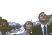 Da heißt es, gelassen bleiben: Vor Jahren hatte Franz Münchinger (Helmut Fischer, rechts) ein flüchtiges Abenteuer mit Carola (Hilde Ziegler). Jetzt ist die Dame nebst Ehemann Hubert (Walo Lüönd) wieder in München und möchte Franz wiedersehen. Doch das Treffen hat einen Haken: auch der Monaco ist inzwischen glücklich verheiratet... also macht man besser nur Sightseeing, wie hier vor dem Münchener Friedensengel.