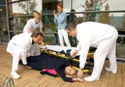 Klinikleiterin Sarah Marquardt (Alexa Maria Surholt, liegend) ist vor den Augen von Pia Heilmann (Hendrikje Fitz, mi.) kollabiert. Dr. Martin Stein (Bernhard Bettermann, vo. li.), Hans-Peter Brenner (Michael Trischan, re.) und ein weiterer Pfleger (Komparse (hi. re.) sind sofort zur Stelle.