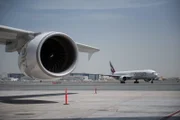 Dubai International Airport - Plane engine with Emirates planes on the runway in the background.
