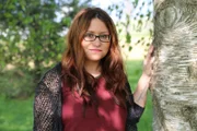 Sabrina standing outside near a tree.