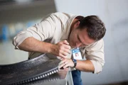 ATSB Investigator Simon Grummett (played by Justin Mader) examines a blackened engine fragment from Qantas Flight 32.