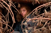 Karo (Nadja Uhl) versteckt sich im dichten Gestrüpp des Waldes.
