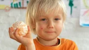 Milo will wissen, wie viele Scheiben eine Mandarine hat und zählt einfach nach.