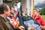 Jerry Paulsen (Peter Marton, liegend) hatte einen Unfall: An seinem Dienstwagen haben die Bremsen versagt. Johanna (Ines Lutz, r.) und ihr Vater Benedikt Beissl (Andreas Geibel, l.) sind zur Stelle, wie der verletzte Jerry in den Krankenwagen geladen wird. Sanitäter (Komparse, 2.v.l.)