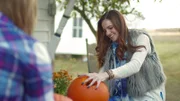 Kate carving a pumpkin.