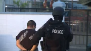 Laredo, TX: A police officer leading away an arrested man.
