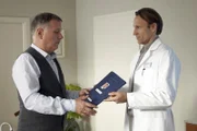 Dr. Martin Stein (Bernhard Bettermann, rechts) ist klar, dass er die ideale Besetzung für den vakanten Chefartposten ist und überbringt Dr. Roland Heilmann  (Thomas Rühmann) siegessicher seine Bewerbung. Als Martin merkt, dass Roland hadert, fragt er nach anderen Bewerbern. Falls dem so ist, würde Martin seine Bewerbung lieber zurückziehen, um Peinlichkeiten zu vermeiden. Für Roland ist damit die Entscheidung gefallen.