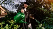 Philipp gießt die Blumen im Garten.