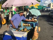 Ein Straßenverkäufer verkauft an einem kleinen Wagen frische Kokosnüsse in La Romana.