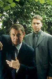 Inspector Barnaby (John Nettles, l.) und sein Assistent, Sergeant Troy (Daniel Casey, r.) sind auf der Suche nach dem unberechenbaren Dean Hunnisett, der als Patient der Mercy Park-Klinik Freigang im Dorf hat.