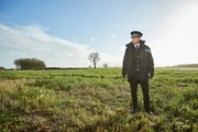 Bill Hixon (Rob Lowe) steht in seiner Uniform auf einer grünen Wiese. Weit und breit ist sonst niemand zu sehen.