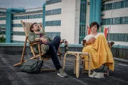 Ben und Joe genießen nach dem Aufdecken des Falles ein kühles Bier und eine Tasse Tee auf dem Dach der Kepler-Universität.