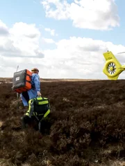 Lisa, die Taschen zum Hubschrauber trägt, über die Moorlandschaft