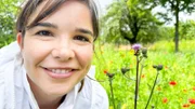 Anna neben einer Honigbiene an einer Blüte. Das fleißige Insekt sammelt Nektar und Pollen als Nahrung für sich und ihr Bienenvolk.