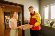 Caro (Meriel Hinsching, l.) nimmt das Paket für Tüffi an und der Paketbote (Florian "Varion" Kiesow, r.) kann nicht aufhören in Caros Gesicht zu starren.