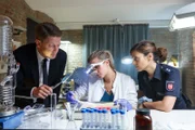 Wolfgang Habedank (Holger Stockhaus, l.) und Süher Özlügül (Sophie Dal, r.) schauen Apothekerin Insa Scherzinger (Theresa Underberg, M.) bei der pathologischen Diagnostik einer abgetrennten Hand über die Schulter.