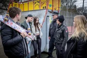 Hans (Bruno F. Apitz, 3.v.r.) und Franzi (Rhea Harder-Vennewald, 2.v.r.) wollen von Sascha (Paul Falk, 2.v.l.) und Jenny (Johanna Werner, 3.v.l.) wissen, was auf der Geburtstagsparty von Lea vorgefallen ist. (Rest: Komparsen).