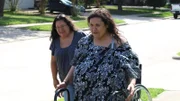 Olivia walking outside the house with her sister in law walking behind her.