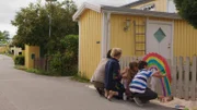 Klara (Paulina Pizarro Swartling) malt mit Mama und Papa einen Regenbogen an den Zaun.