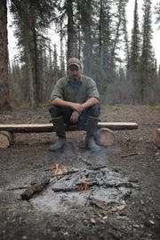 Scott reflecting by the fire, looking into the fire.