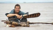 Bear Grylls sits in zebra skin canoe.