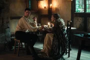 In the present day, Domenico finds a brutalised body in Oxford and suspects a mysterious affliction called blood rage has returned. In 1590, Matthew is forced to beg forgiveness from Father Hubbard for executing Tom Caldwell – the sort of conflict he had hoped to avoid. Diana and Matthew are introduced to John Dee by Mary Sidney. They explore his library, hoping to find clues to the whereabouts of the Book of Life. Dee tells them his scryer Edward Kelley stole a valuable book from him and is now hiding in Bohemia, and Matthew and Diana suspect it must be the Book of Life. Goody Alsop teaches Diana about weaving and knots, and Diana is overwhelmed to discover a new world of magic open up to her. In the present, Em practises higher magic to try and reach Diana’s mother, Rebecca, in order to help her niece get closer to the Book. Matthew suspects that Kit has betrayed Diana’s identity to Cecil. A cautious Matthew and Diana meet with Queen Elizabeth I, who accuses Matthew of betraying her by marrying Diana. As a test of loyalty, she orders them to bring Edward Kelley home from the clutches of King Rudolf, so that she can claim the Philosopher’s Stone, the secret to eternal life which Kelley had promised. Before they can leave however, Gallowglass arrives with a message from Matthew’s father Philippe – summoning Matthew and Diana to France.