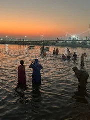 Gläubige Hindus nehmen bei Sonnenuntergang ein Bad im Ganges.