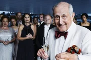 Will Gutes tun: Walter Loving (Hans Hollmann) begrüsst die VIP-Gäste zum Benefizkonzert. Im Bildhintergrund: Die Pianistin Miriam Goldstein (Teresa Harder), der Dirigent Gidon Winternitz (Gottfried Breitfuss) und die Konzertorganisatorin Silvia Bosshardt (Heidi Maria Glössner).