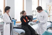 Nach einem Feuerwehreinsatz kommt die Feuerwehrfrau Katharina Bischof (Theresa Scholze, M.) mit Verbrennungen in die Notaufnahme und wird dort sofort von Elias Bähr (Stefan Ruppe, r.) und Chefärztin Patzelt (Marijam Agischewa, l.) behandelt.