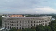 Das inzwischen halb zugewachsene Zeppelinfeld in Nürnberg, welches von hohen Mauen umgeben ist, umfasst die Fläche von zwölf Fußballfeldern.