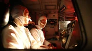 Astronauts at control panel.