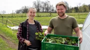Marie Woeste und Lewis Zierke mit einer Kiste frisch geerntetem Salat.