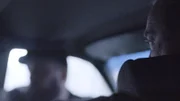 Zwei Männer sitzen im Auto.