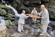 Geun Bum Sunim, Wookwan Sunim und Yeon il Sunim (v.l.) waschen Wurzeln im Fluss.