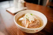 „Pyongyang Naengmyeon“ stammt aus der Hauptstadt Nordkoreas und besteht aus langen Buchweizennudeln in kalter Rinderbrühe die in der Regel mit dünn geschnittenen Birnen, Gurken, einem gekochten Ei und weißem Rettich-Kimchi serviert werden. Es wird hier im „Woo Lae Oak“ serviert und ist ein beliebtes Sommergericht, das in Seoul genossen wird und für die nordkoreanischen Auswanderer der Stadt eine Erinnerung an die Heimat ist. „Pyongyang Naengmyeon“ stammt aus der Hauptstadt Nordkoreas und besteht aus langen Buchweizennudeln in kalter Rinderbrühe die in der Regel mit dünn geschnittenen Birnen, Gurken, einem gekochten Ei und weißem Rettich-Kimchi serviert werden. Es wird hier im „Woo Lae Oak“ serviert und ist ein beliebtes Sommergericht, das in Seoul genossen wird und für die nordkoreanischen Auswanderer der Stadt eine Erinnerung an die Heimat ist.