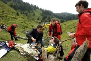 Simon Brandl (Constantin Gastmann) ist beim Mountainbikerennen schwer gestürzt. Hans (Heiko Ruprecht, 2.v.r.) hat Martin (Hans Sigl, l.) zu Hilfe gerufen.
