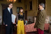 Lady Gabby (Eleanor Tomlinson, M.) ist aufgeregt. Endlich treffen sie und Greg (Stephen Merchant, l.) ihren Vater (Richard E. Grant, r.), um über ihr heißersehntes Festival zu sprechen.