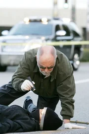 Drei Teenager wurden mit einer Maschinenpistole niedergestreckt. Gerichtsmediziner Dr. Albert Robbins (Robert David Hall) untersucht die Leichen.