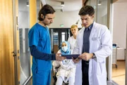 Assistenzarzt Ivo Maric (Jakob D'Aprile, li.) und Oberarzt Dr. Ben Ahlbeck (Philipp Danne, re.) entdecken eine postoperative Komplikation, die bei Filiz Basarni (Tua El-Fawwal, mi. mit Komparse) Schuldgefühle auslöst.