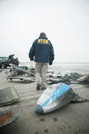 REENACTMENT - NTSB-Ermittler Tom Haueter (gespielt von Christian Lloyd) untersucht die Trümmer zweier Flugzeuge, die nach einem tödlichen Zusammenstoß auf dem Quincy Regional Airport verstreut wurden.