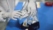 Close-up of gloved hands sealing material over satellite.