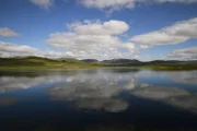 Landschaft mit einem See und schneebedeckten Bergen im Hintergrund.