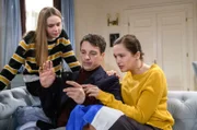Im Beisein von Valentina (Paulina Hobratschk, l.), erhalten Eva (Uta Kargel, r.) und Robert (Lorenzo Patané, M.) schlechte Neuigkeiten, bezüglich ihrer anstehenden Reise.
