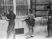 Die junge Französin in ihrer Einsatzkleidung hält sich dicht an einer Wand und hält ihre Maschinenpistole bereit, um im Handumdrehen zu schießen. Sie gehört zu einer Patrouille, die deutsche Scharfschützen aufspüren soll, die sich noch in Paris verstecken.