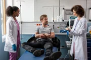 Frank Boger (Christoph Kottenkamp, M.) wird in die Notaufnahme eingeliefert. Nach einem Motorradsturz stellt Emma Jahn (Elisa Agbaglah, l.) die Diagnose. Prof. Dr. Karin Patzelt (Marijam Agischewa, r.) kommt dazu und stellt sich dem Patienten vor.