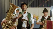 Der Flüchtling Alfons Nkmura (Dimitri Abold, M. mit Komparsen), genannt Fonsi darf die Goaßlschnalzer in den prestigeträchtigen Wettkampf führen.